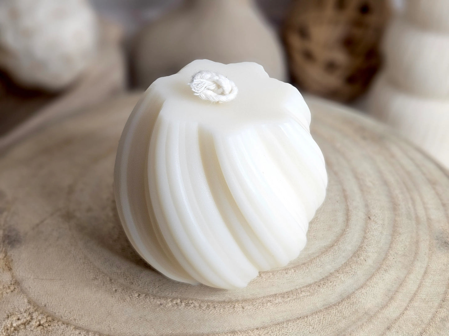 Bougie Aura - Boule Sculptée avec Vrilles, vue 3/4 haut, avant. Cette bougie en forme de sphère avec des vrilles sculptées est disponible en 4 parfums (Ambre, Amor Mio, Fleur de Coton, Vanille Gourmande) pour créer une atmosphère apaisante et parfumée dans n’importe quel espace. | La P'tite Mèche - Laptitemeche.com