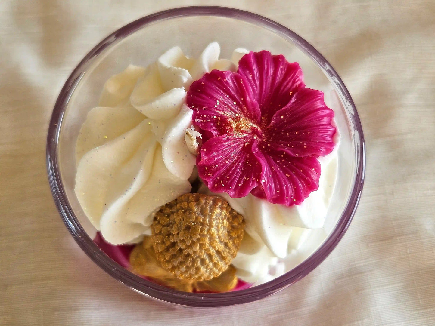 Vue plongeante sur le Bouddha doré et la fleur de cerisier reposant sur une chantilly de cire onctueuse.