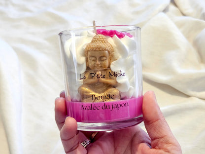 Grande bougie de luxe Azalée du Japon tenue en main, mettant en valeur la statue de Bouddha artisanale.