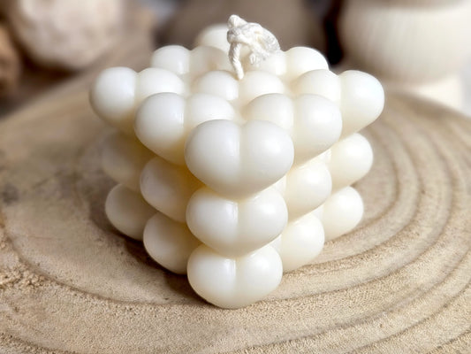 Bougie Carré d'Amour - Cube en Cœurs Sculptés, vue 3/4 haut, avant. Cette bougie en forme de cube constitué de petits cœurs sculptés est disponible en 4 parfums exquis : Ambre, Amor Mio, Fleur de Coton et Vanille Gourmande, créant une atmosphère romantique et chaleureuse dans votre espace. | La P'tite Mèche - Laptitemeche.com