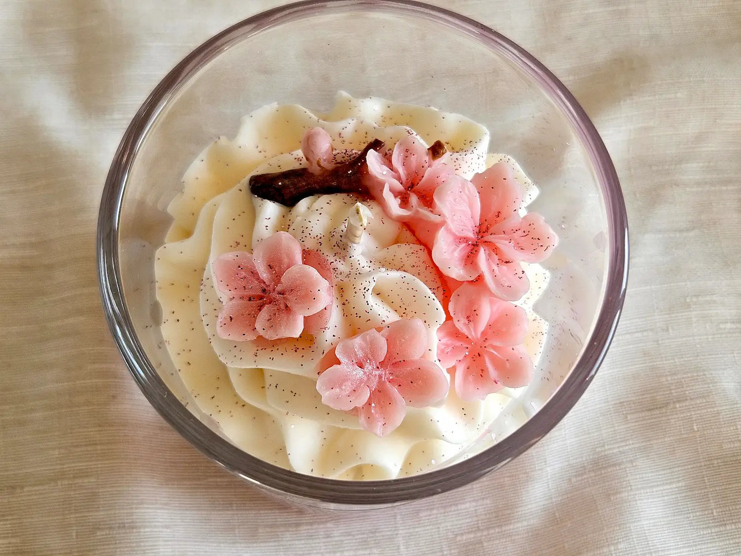 Vue plongeante 190g : fleurs de Sakura en cire d'olive sur une chantilly blanche aérienne.