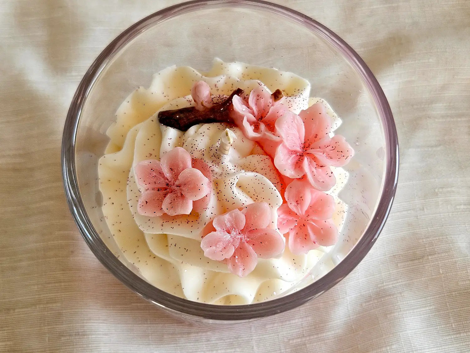 Vue plongeante 190g : fleurs de Sakura en cire d'olive sur une chantilly blanche aérienne.
