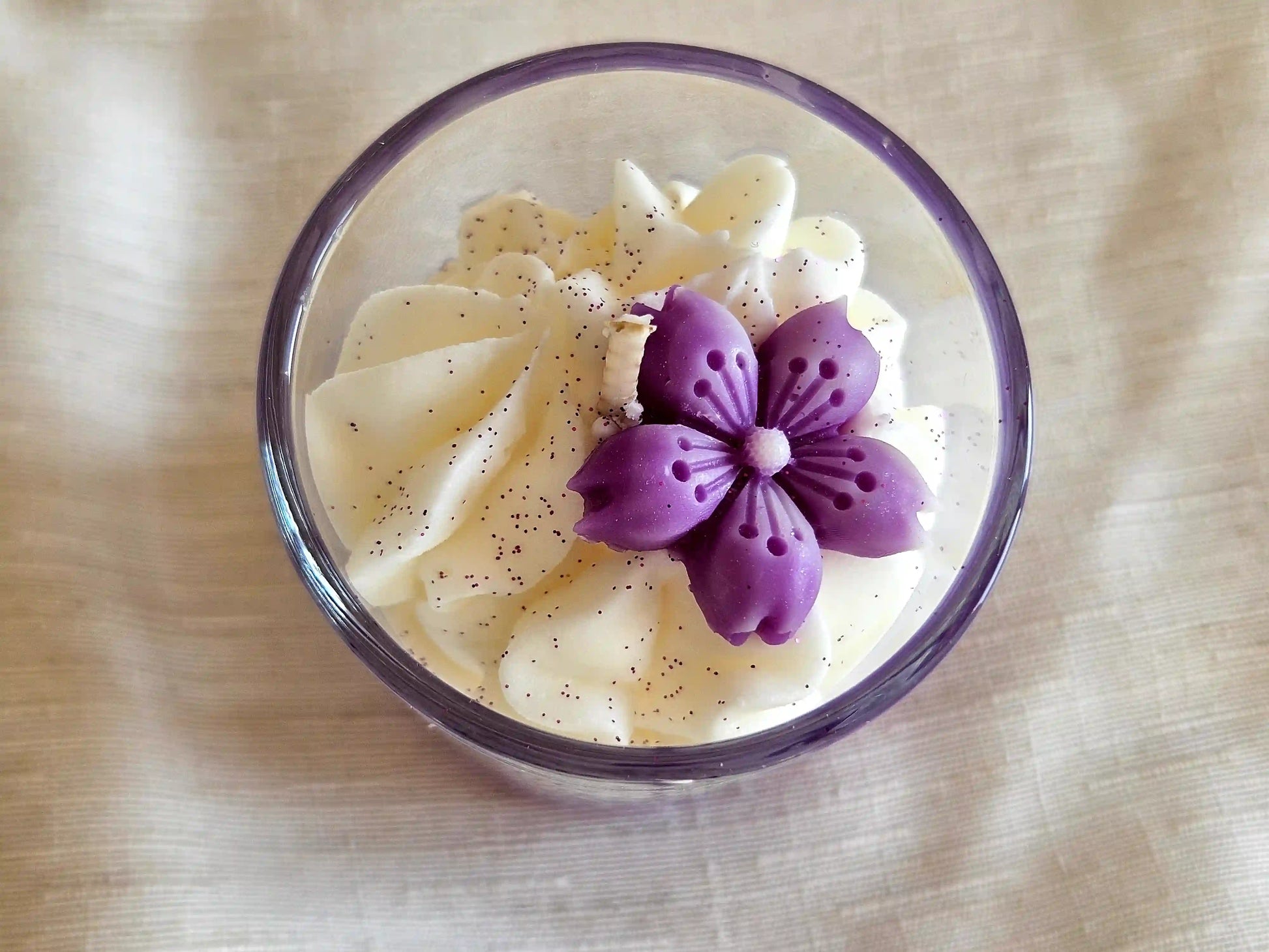 Gros plan sur la chantilly blanche et la fleur de violette artisanale sculptée en cire.