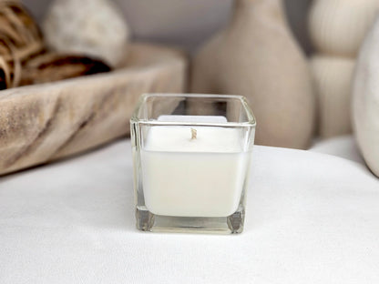 Vue de profil d'une bougie artisanale à la citronnelle montrant une cire végétale blanche immaculée dans un verre carré.