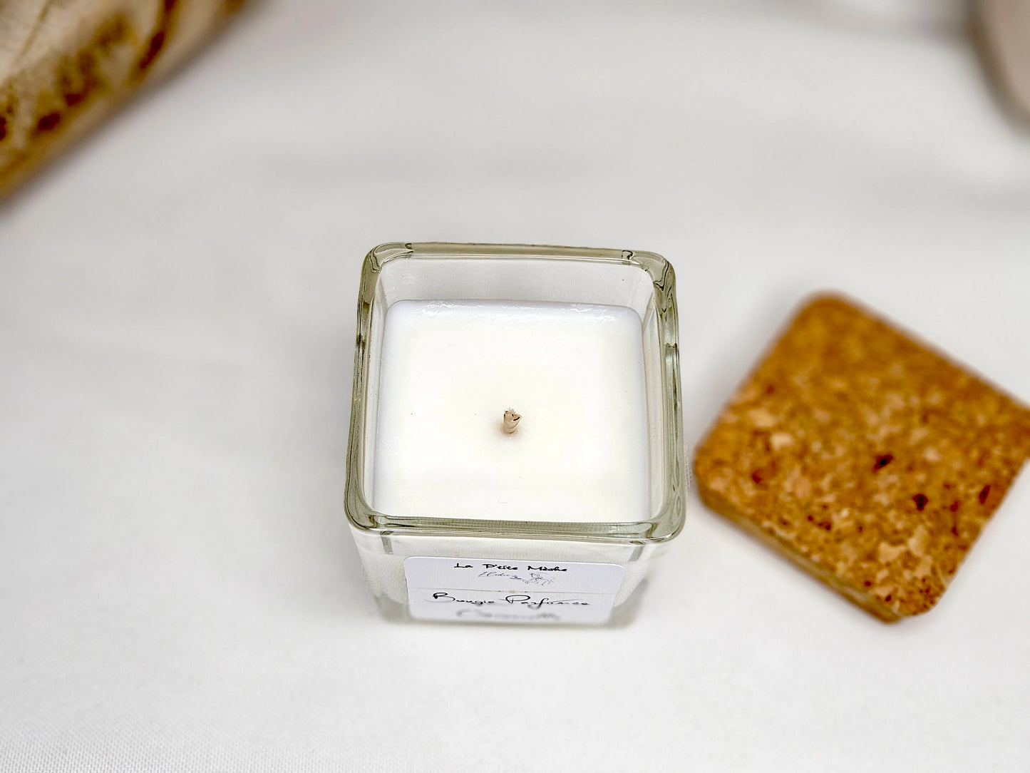 Vue de dessus d'une bougie à la citronnelle dans un pot carré, montrant la mèche en coton centrée et la cire végétale blanche