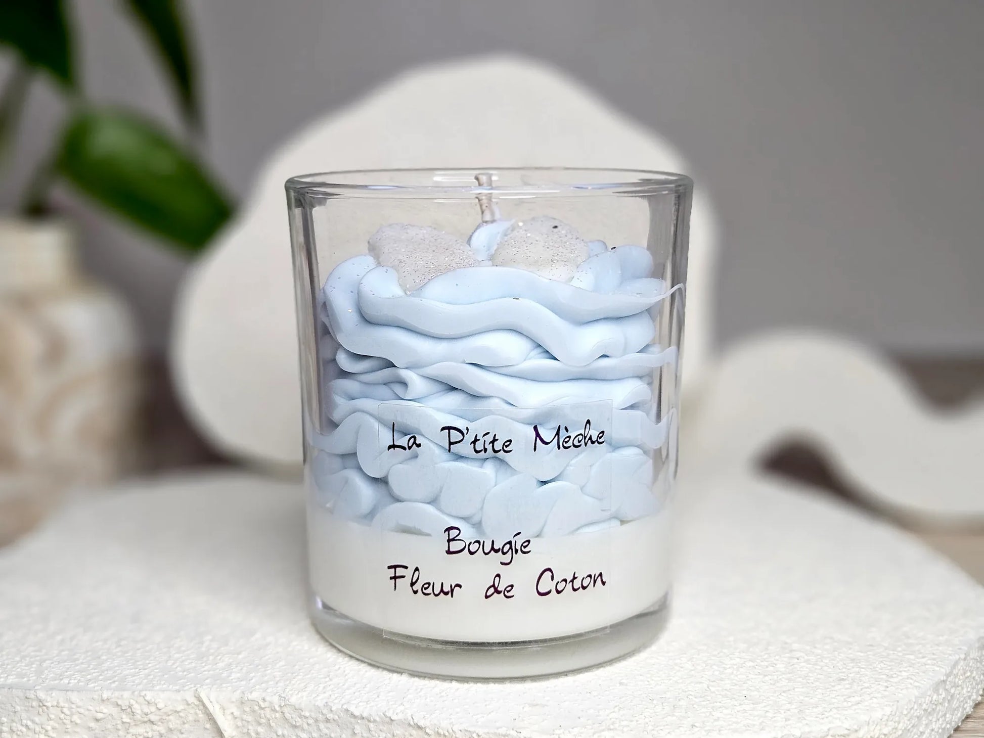 Grande bougie gourmande Fleur de Coton 190g avec dôme de chantilly bleu ciel et décors pailletés, parfum de Grasse linge frais.