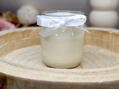 Vue arrière d'une bougie artisanale Lait de Riz dans un pot en verre blanc givré, montrant l'onctuosité de la cire végétale et le ruban en satin blanc.