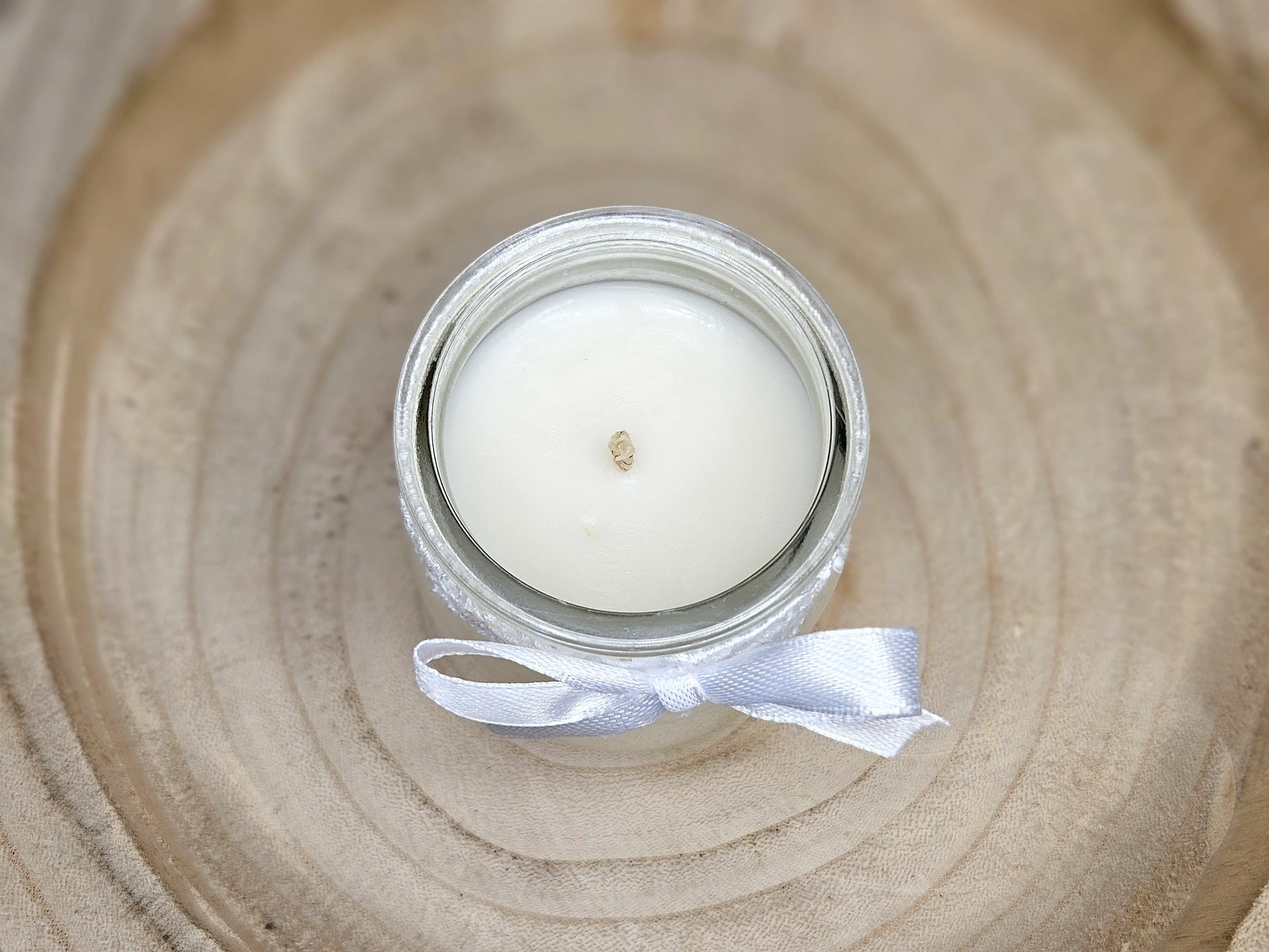 Vue aérienne d'une bougie artisanale au lait de riz montrant la mèche centrale et la texture lisse de la cire végétale blanche.