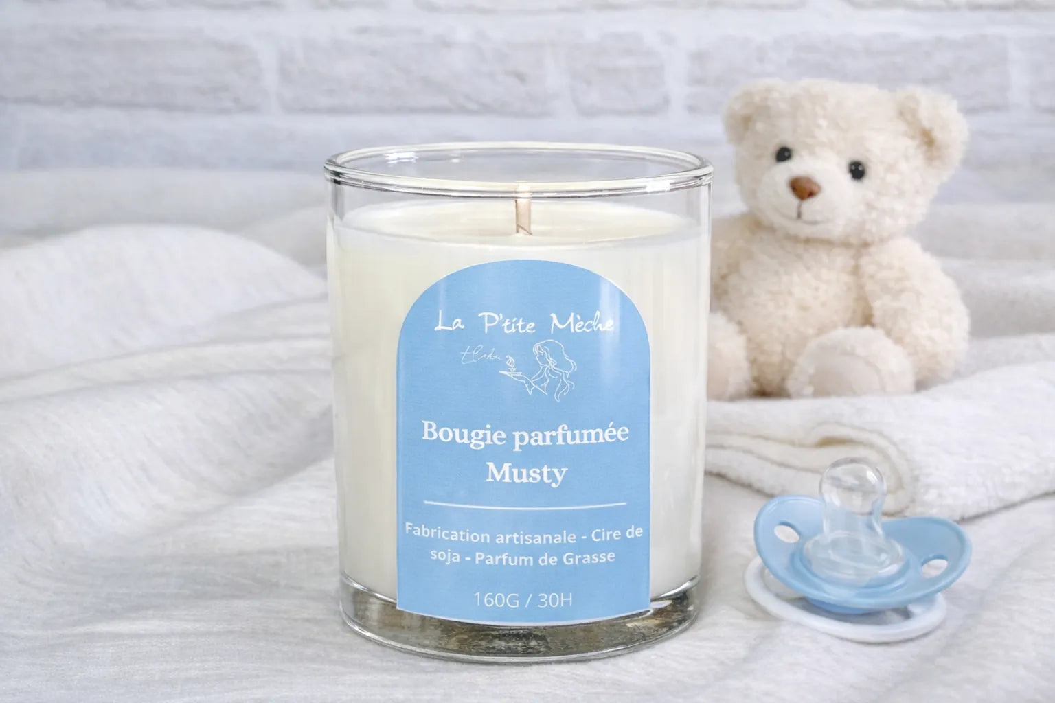 Bougie artisanale Musty La P'tite Mèche, parfum de Grasse senteur poudre de bébé et coton propre, décor avec ours en peluche