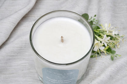 Vue du dessus d'une bougie blanche au Chèvrefeuille avec fleurs fraîches en arrière-plan, fabrication française à la main