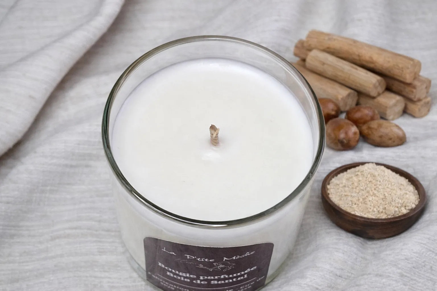Gros plan mèche coton et cire de soja blanche d'une bougie naturelle Bois de Santal vue du dessus, poudre de santal en arrière-plan