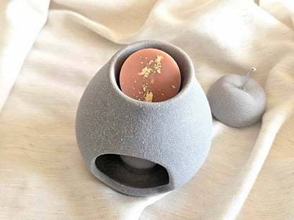 Fondant parfumé au lait d'amande déposé dans la coupelle d'un brûleur en ciment gris, prêt pour une diffusion gourmande.