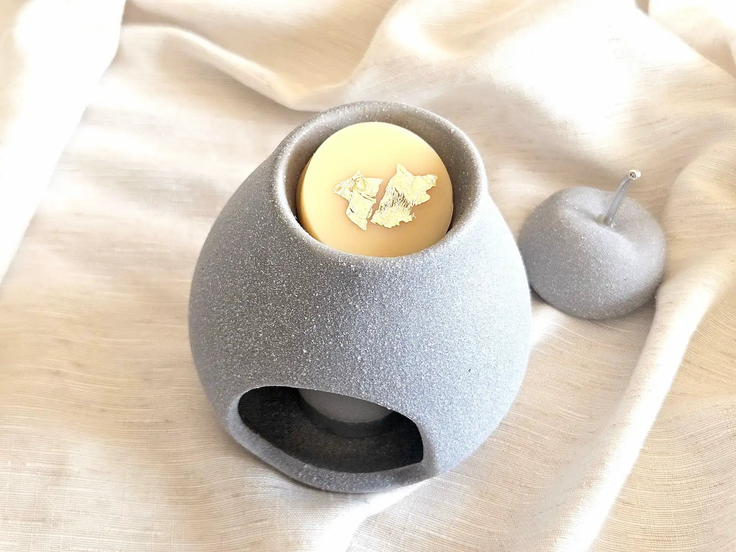 Fondant végétal à la vanille déposé dans la coupelle d'un brûleur en ciment gris, prêt pour une diffusion douce et sucrée.