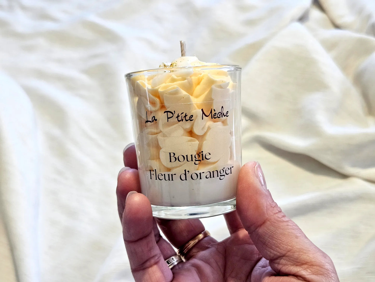 Idée cadeau invité mariage : petite bougie Fleur d'Oranger tenue en main, artisanat local de luxe.