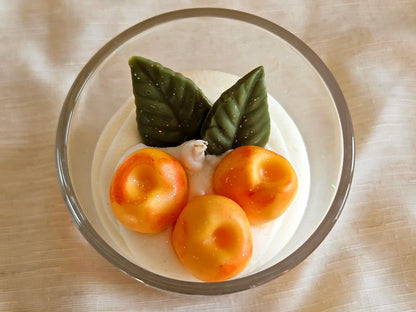 Vue plongeante sur les trois mirabelles en cire d'olive et feuilles vertes sur chantilly onctueuse.