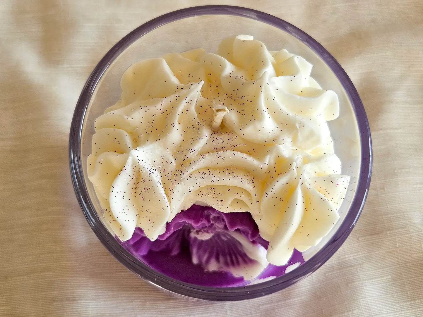 Vue du dessus de la bougie Violette 190g : chantilly onctueuse et fleur violette en décor.