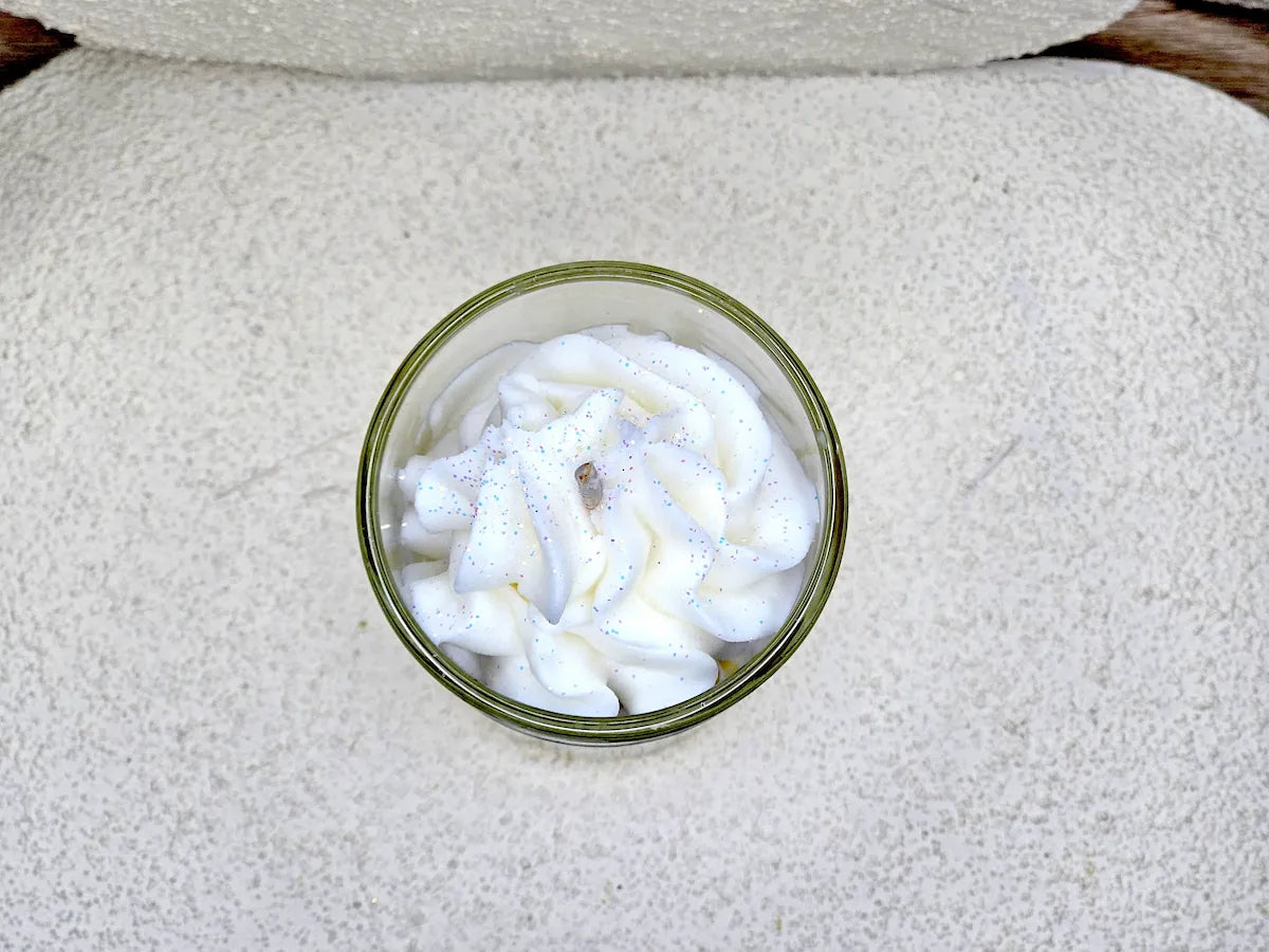 Vue de haut de la petite bougie banane, focus sur la texture réaliste de la chantilly de cire et la mèche en coton.