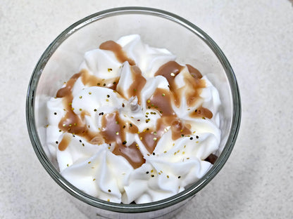 Gros plan sur le coulis en cire et les éclats décoratifs sur le dôme d'une bougie gourmande à la madeleine.