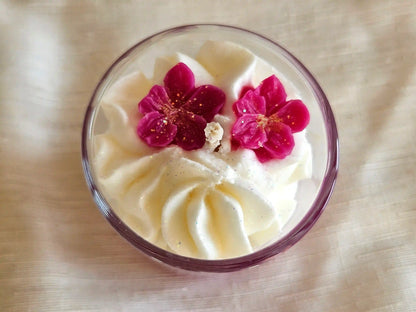 Gros plan sur les fleurs de cerisier roses sculptées en cire d'olive sur une chantilly de soja blanche.