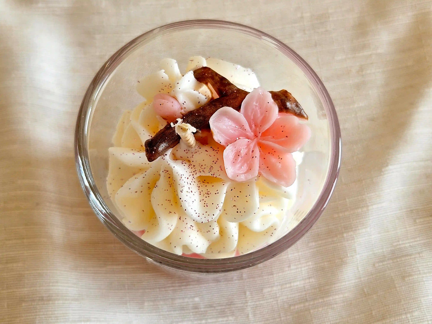 Détail artisanal : fleurs de Sakura en cire d'olive sur une chantilly de cire de soja onctueuse.