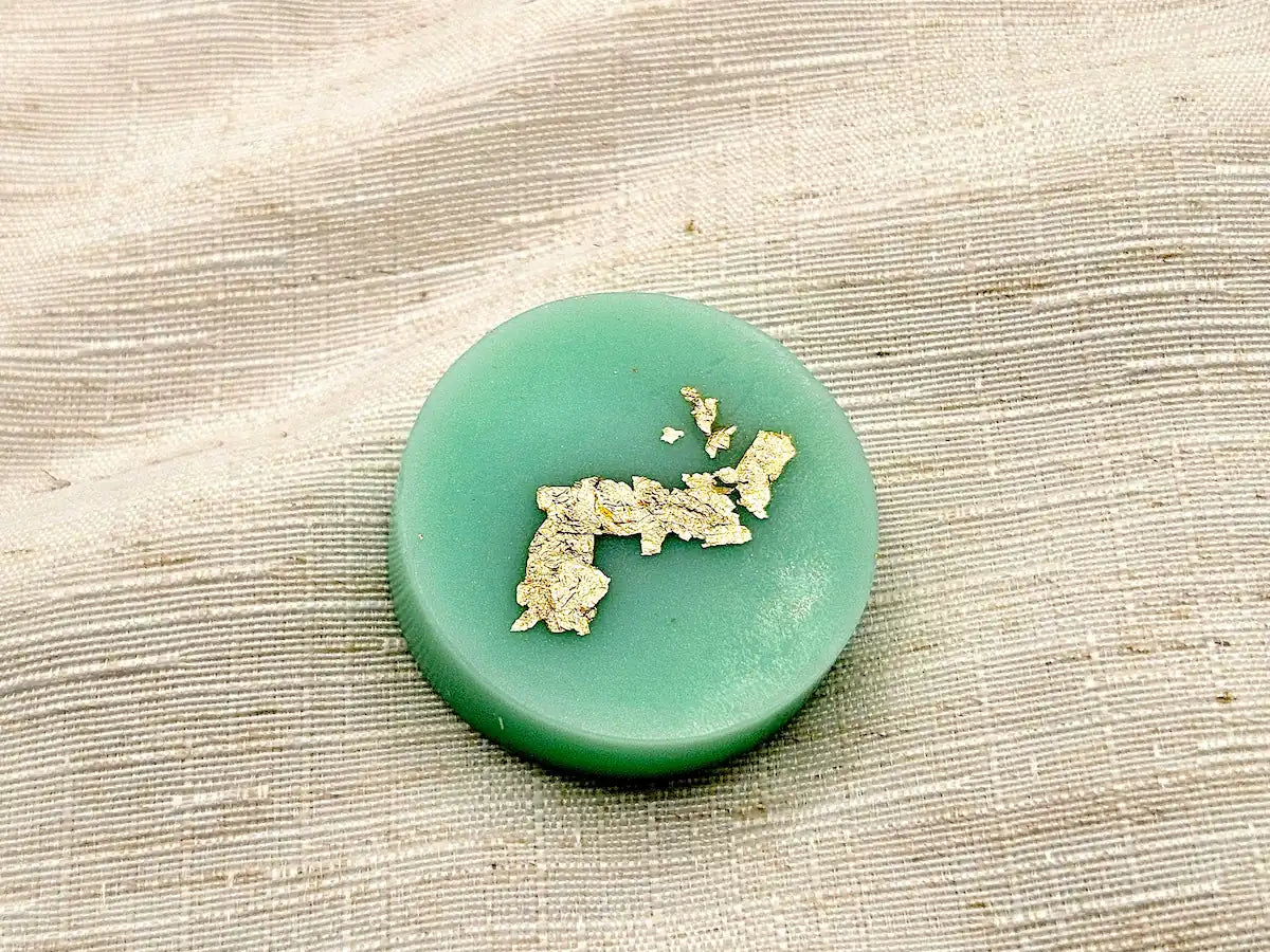 Palet fondant parfumé Menthe et Basilic, couleur vert d'eau avec dorure à la feuille d'or, sur fond de lin naturel.