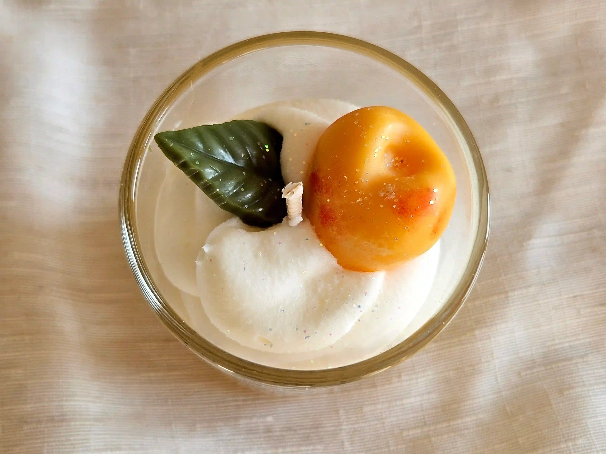 Gros plan sur le fruit mirabelle sculpté en cire d'olive déposé sur une chantilly de cire de soja.