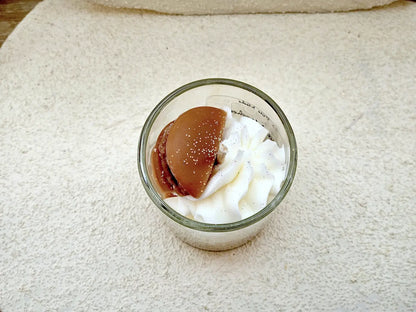 Focus sur la mèche coton et le mini macaron décoratif d'une bougie parfumée aux notes de pâtisserie fine.