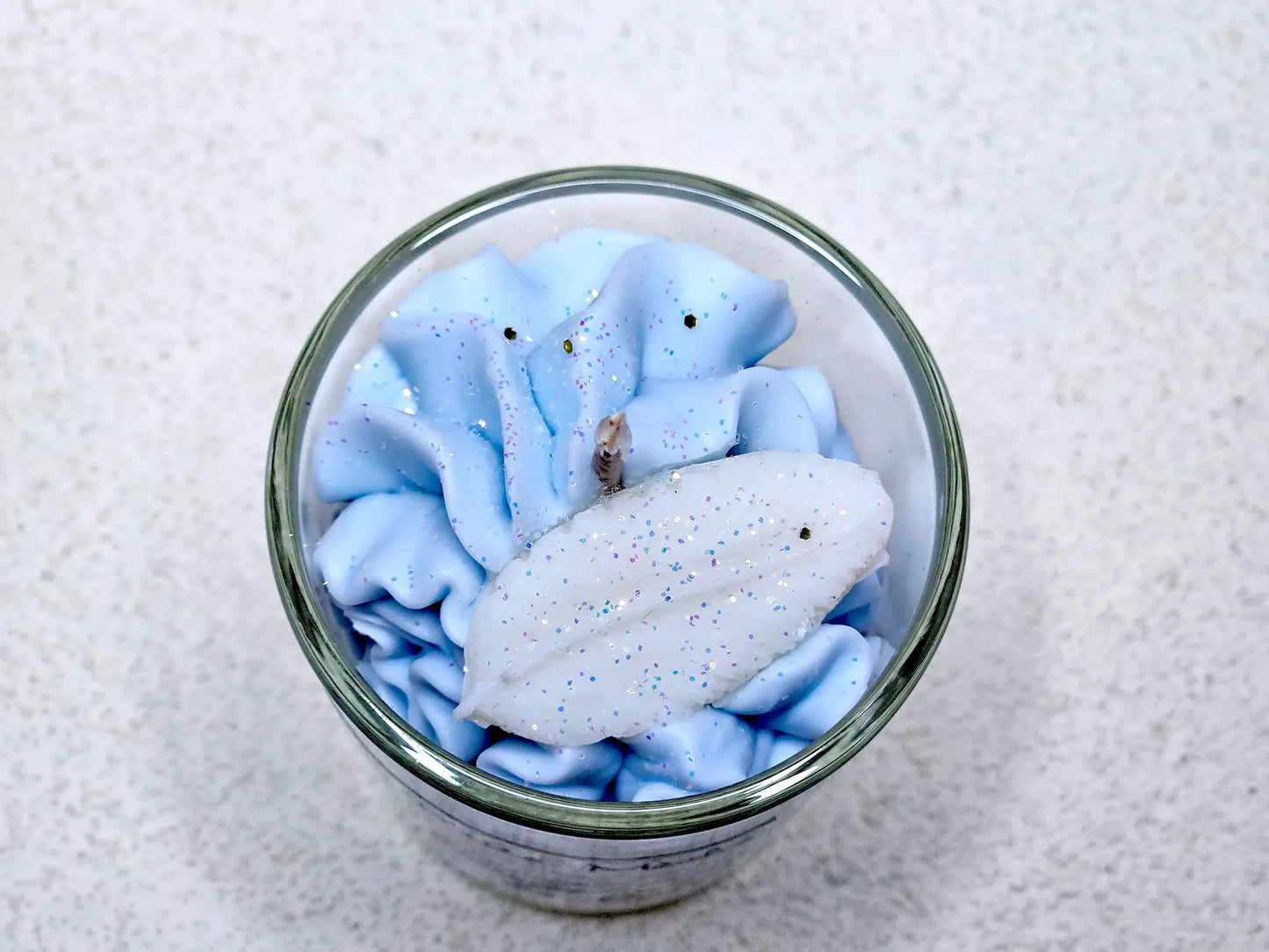 Détail de la mèche coton et des décors délicats sur une petite bougie gourmande aux notes de fleurs blanches.