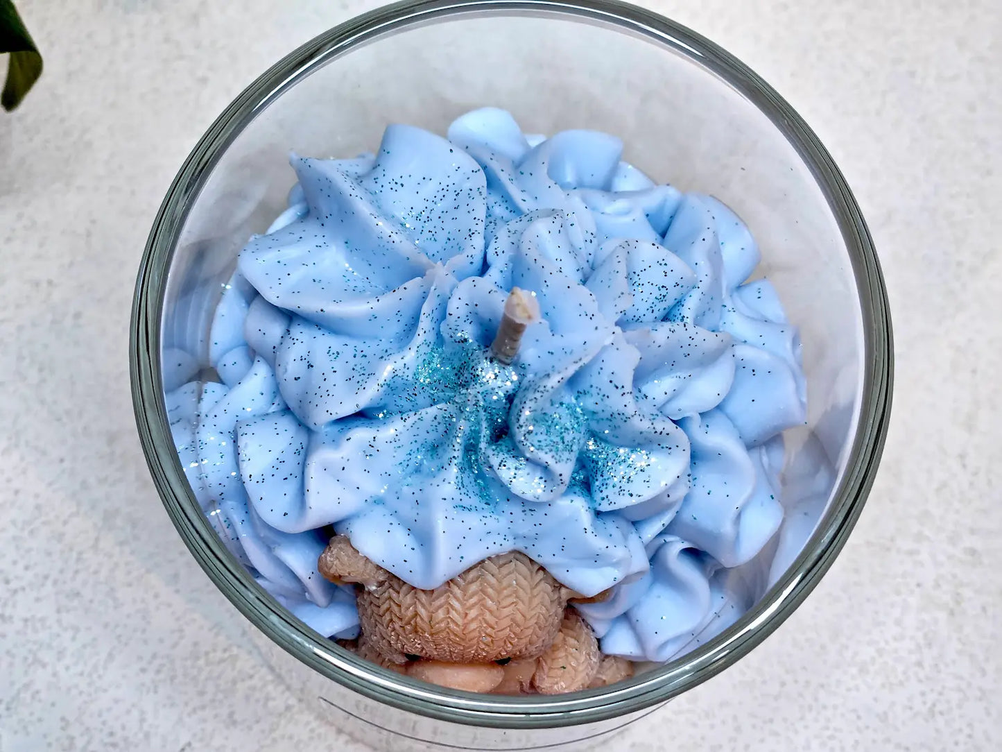 Gros plan sur le nounours en cire blotti dans une chantilly de cire bleue, décor réconfortant de **ma** fabrication artisanale.