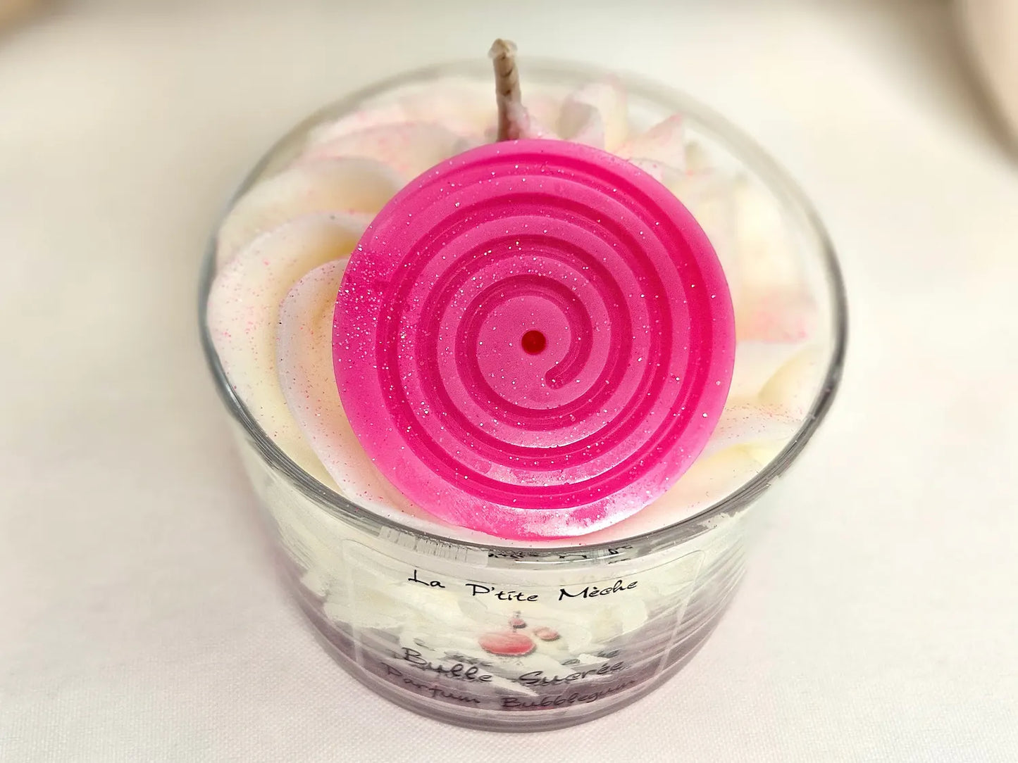 Gros plan sur le décor ludique en cire sur le sommet d'une bougie gourmande parfumée au chewing-gum rose.