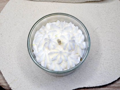 Gros plan sur le dôme de meringue en cire fouettée d'une bougie gourmande, mèche coton centrée pour une combustion parfaite.