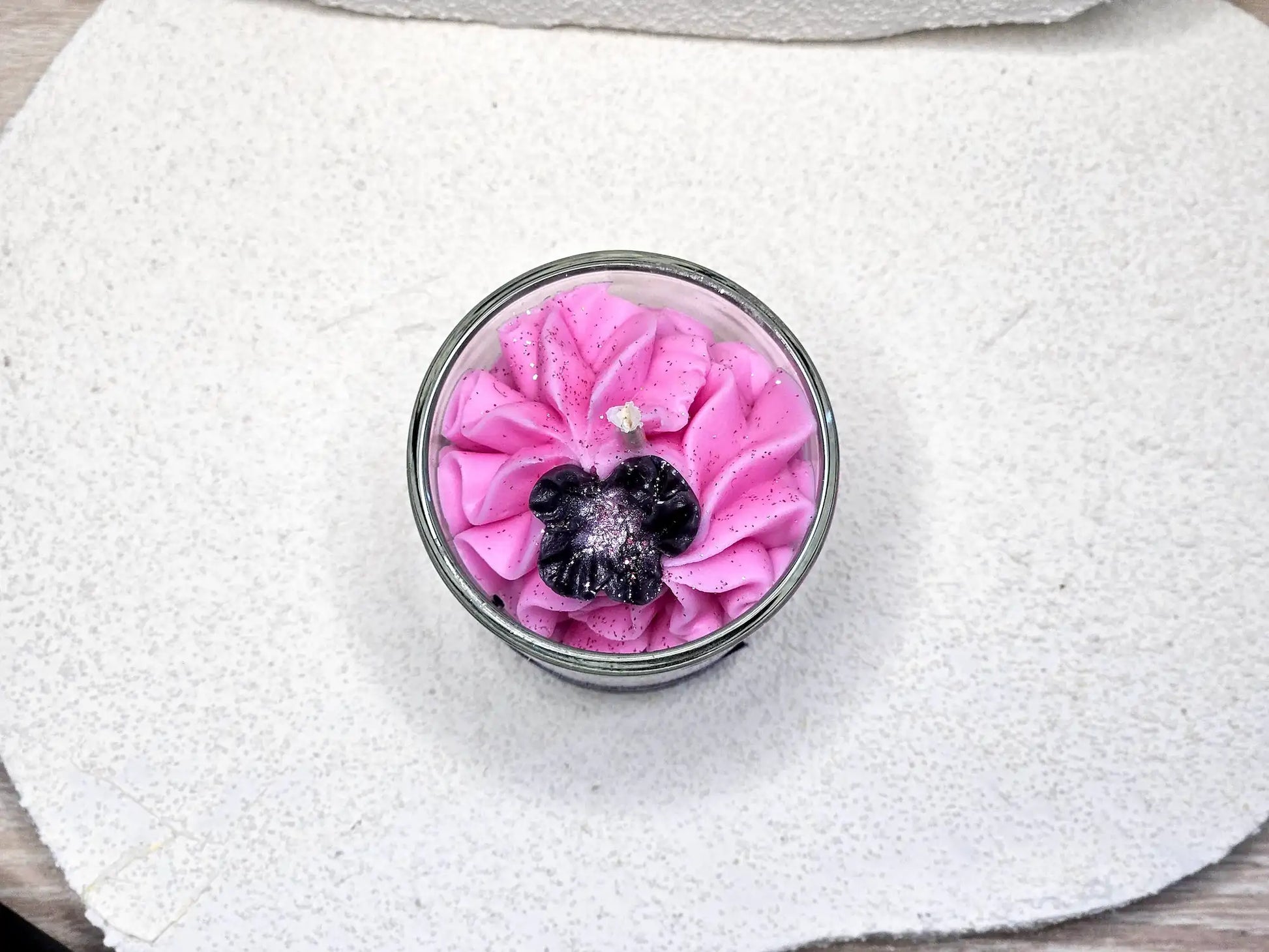 Vue plongeante sur la petite bougie Orchidée Noire mettant en valeur la mèche en coton et les détails de la fleur décorative.